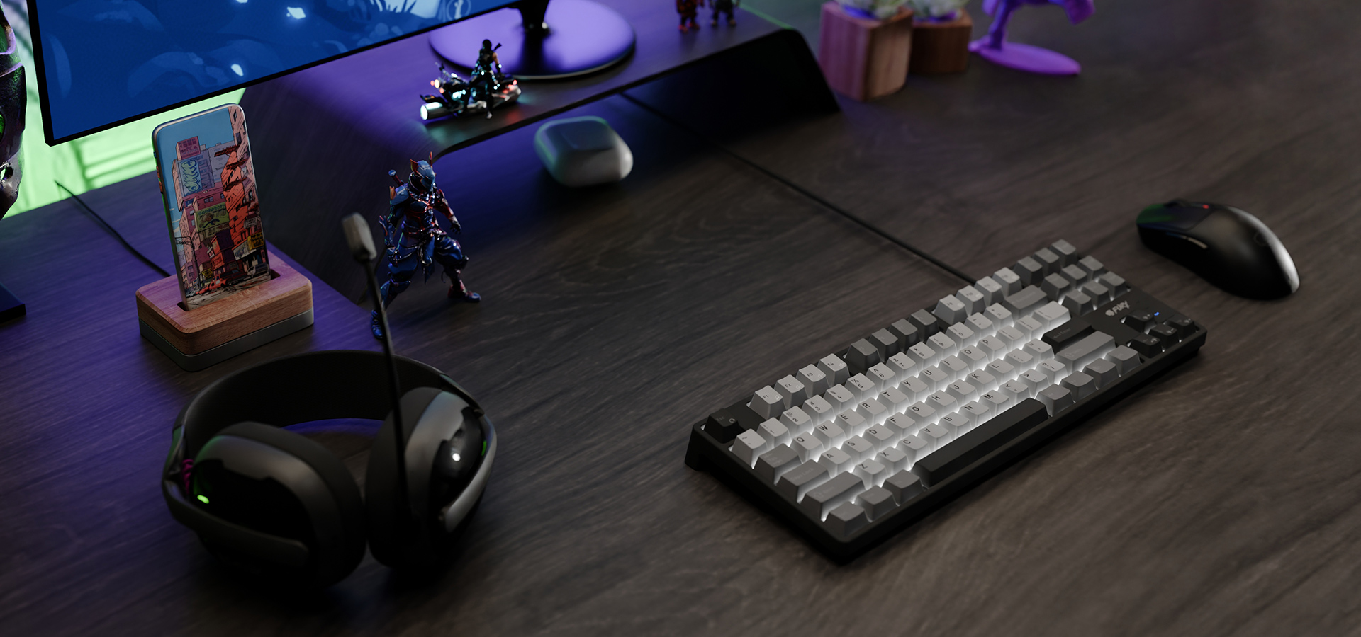 Na ciemnym drewnianym biurku znajdują się klawiatura, mysz oraz zestaw słuchawkowy obok figurek.