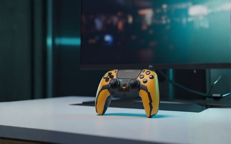 Żółty kontroler YAXO Hornet Fury Elite stojący na biurku przed monitorem