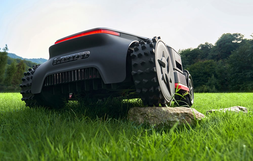 Robot koszący pokonuje przeszkodę w postaci kamienia na trawniku