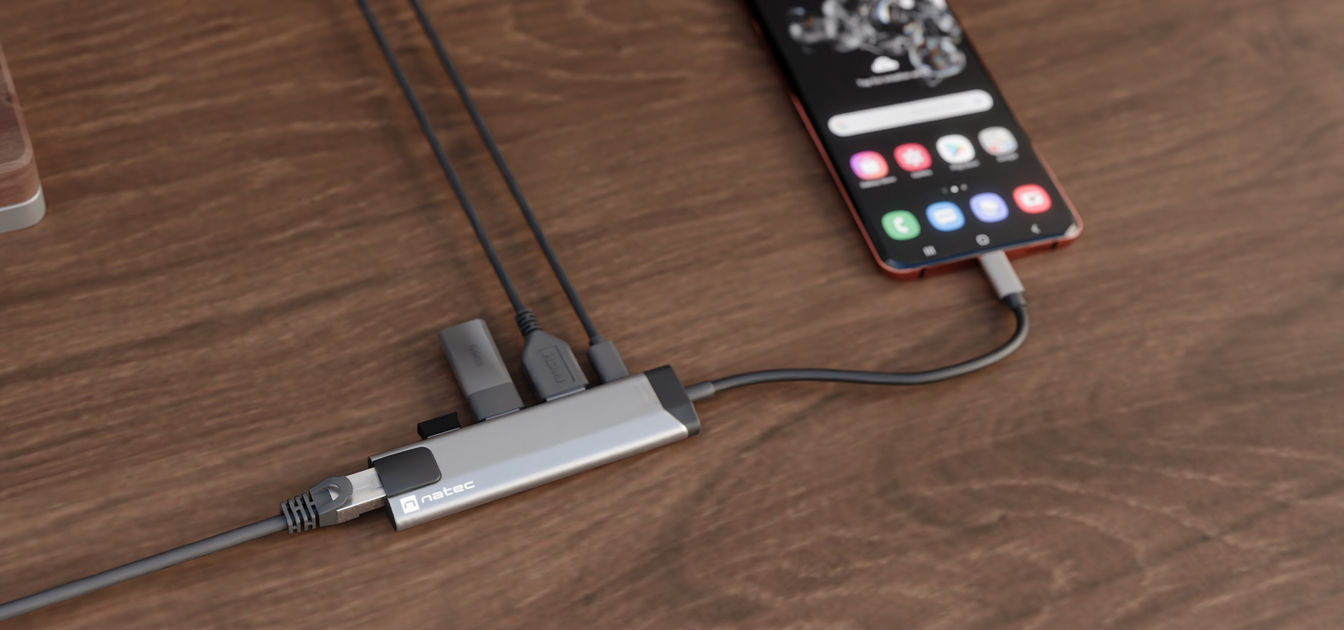 Adapter z wieloma portami podłączony do smartfona na drewnianej powierzchni