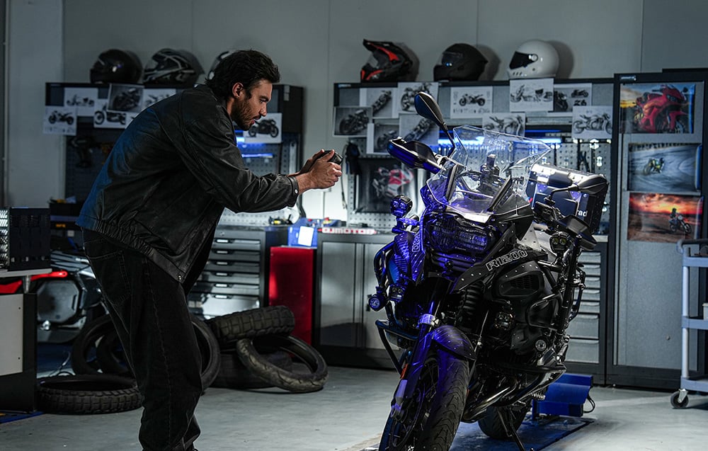 Mężczyzna w warsztacie motocyklowym skanuje ręcznym skanerem przód motocykla