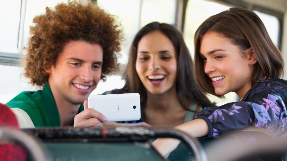 Grupa znajomych patrząca na ekran telefonu Xperia E4