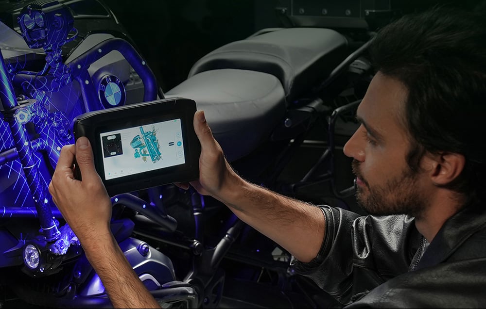 Mężczyzna w skórzanej kurtce trzyma skaner 3D skierowanym na silnik motocykla BMW