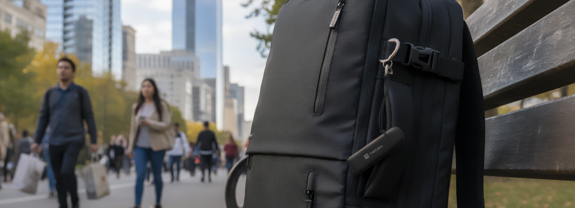 Czarny czytnik kart zamontowany na plecaku, z krajobrazem miasta i pieszymi w tle