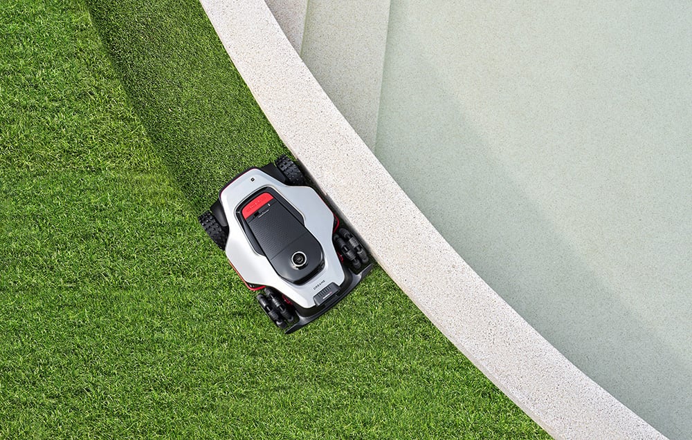 Robot koszący kosi trawę wzdłuż krawędzi basenu