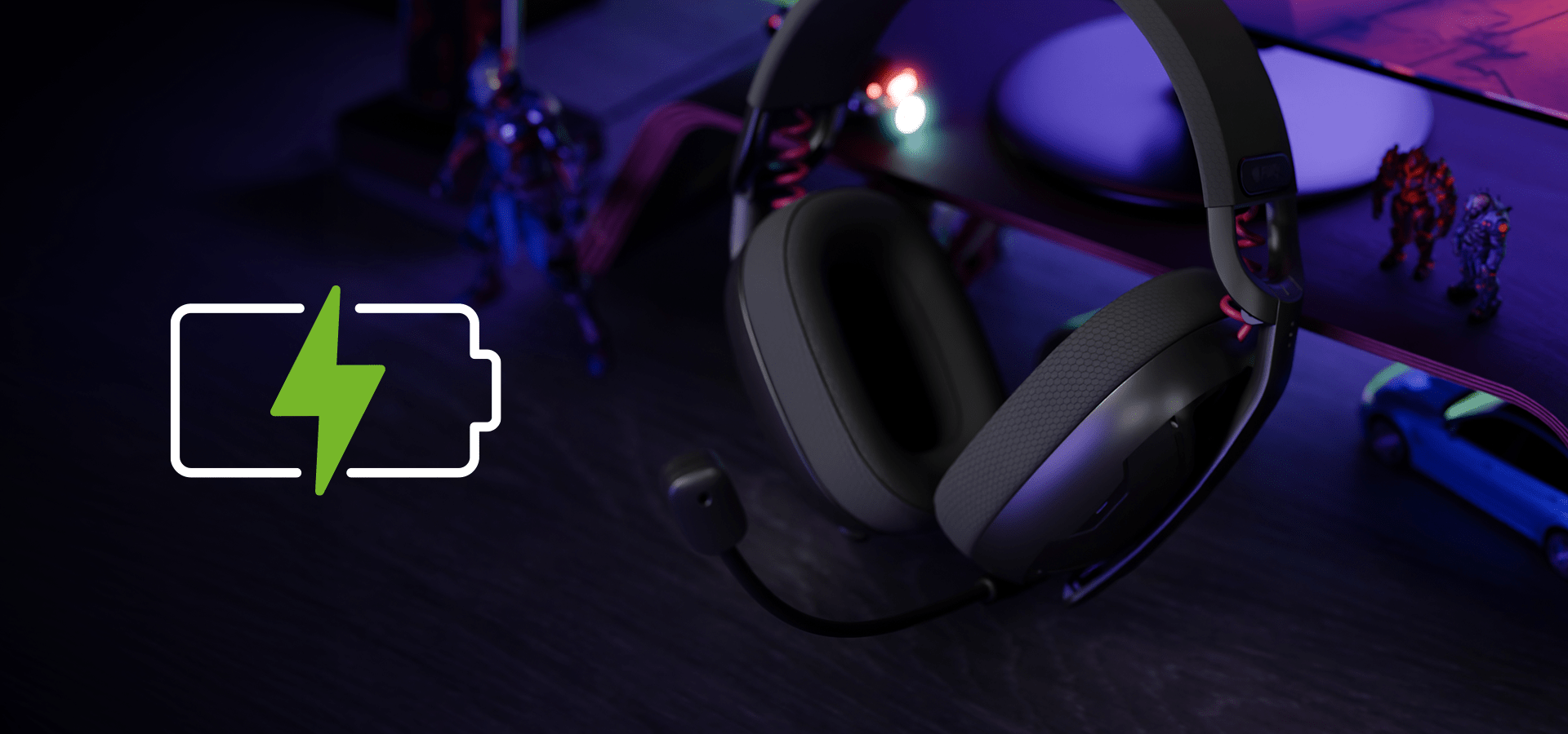 Czarne słuchawki bezprzewodowe z mikrofonem, umieszczone na ciemnej powierzchni obok zabawek i ikony ładowania.