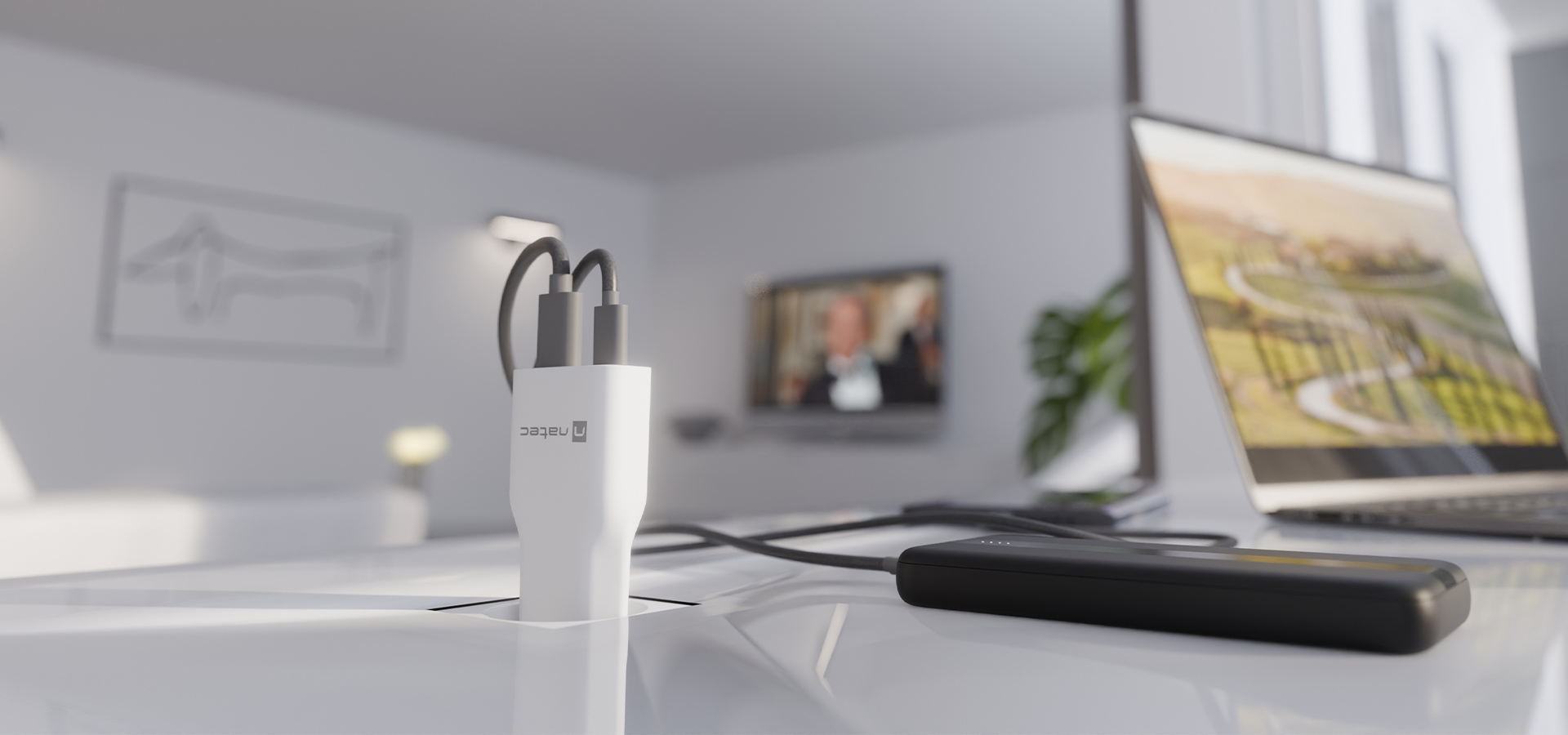 Biały adapter do ładowania z dwoma kablami podłączonymi do niego na biurku z laptopem.