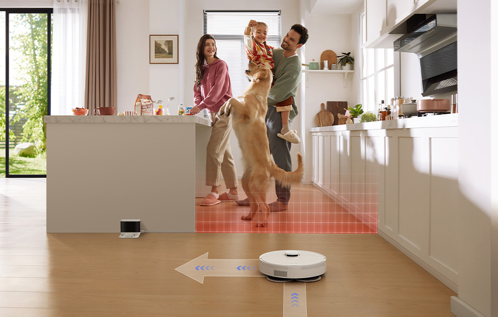 Rodzina z dzieckiem i psem w kuchni. Obok sprząta robot.