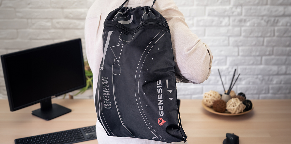 Plecak sportowy ze sznurkiem i logo Genesis, noszony na plecach, w nowoczesnym otoczeniu miejsca pracy.