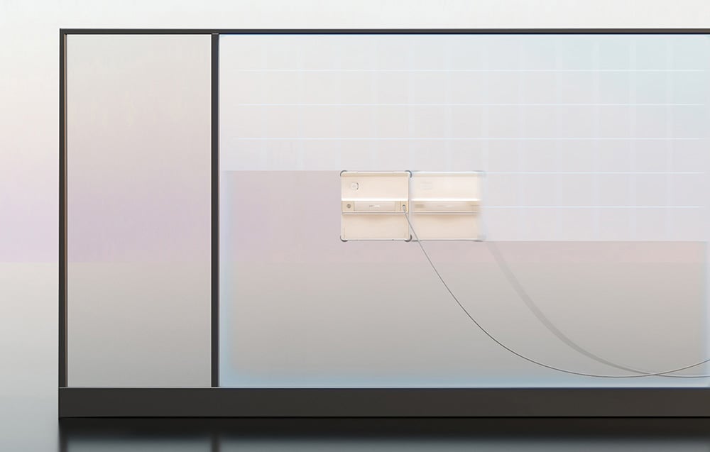 Dwa roboty czyszczące przyklejone do dużej szklanej powierzchni