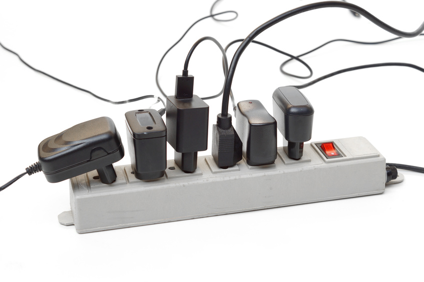 Many plugs and adapters plugged into electric power bar