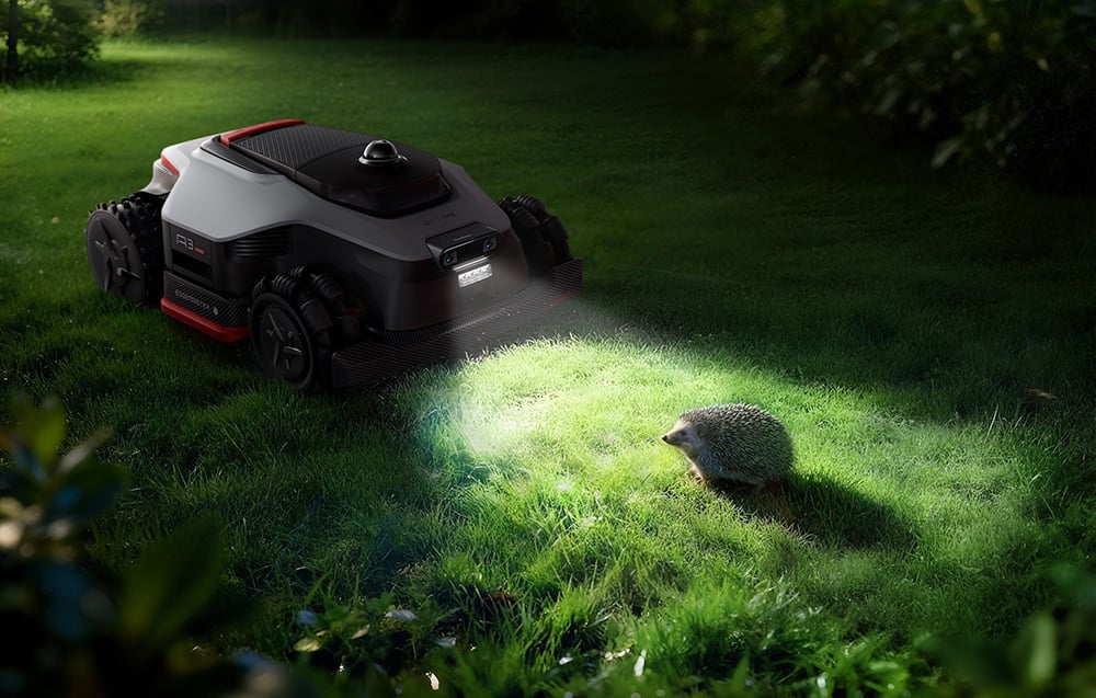 Robot koszący świeci wbudowaną lampą na jeża na trawniku nocą